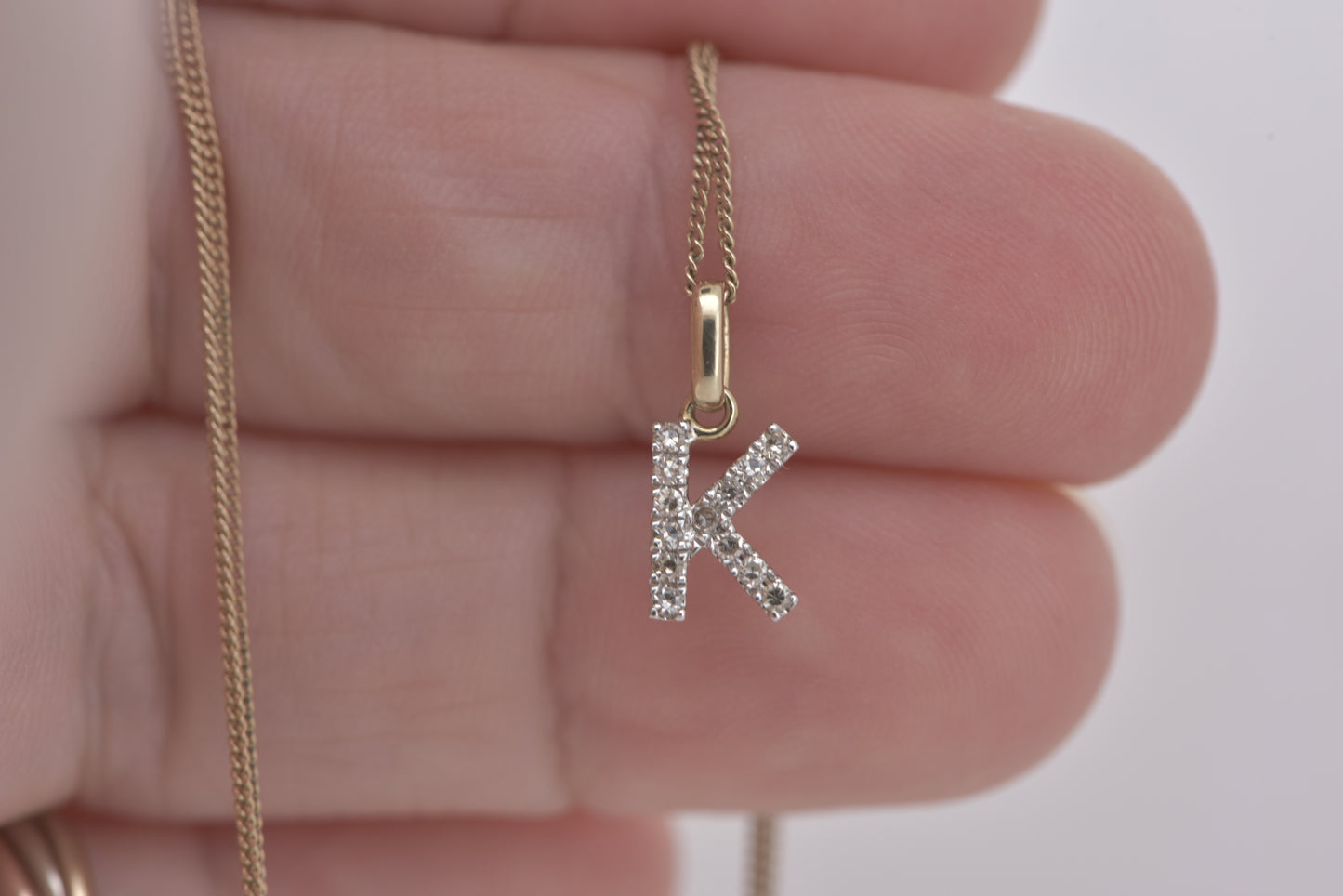 Letter K diamond in white gold with yellow gold bale